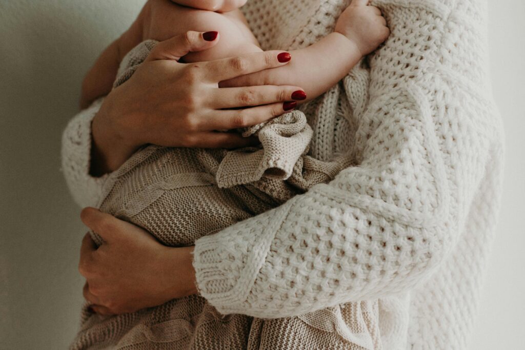 Close-up of a mother holding her baby in warm knitwear, conveying love and togetherness.